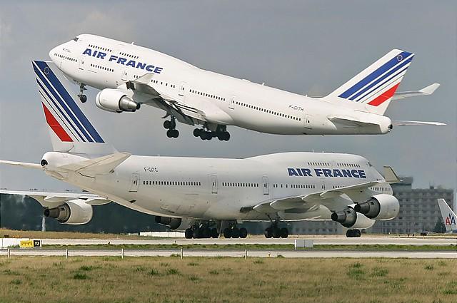Two Boeing 747-400s of Air France, one climbing out while the other taxis. 
