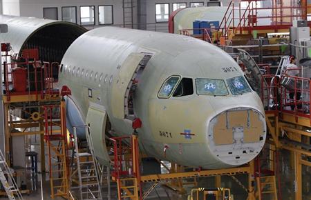 An employee stands next to an A320 plane under construction in Tianjin municipality